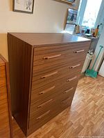 Front and top view of wooden chest of drawers showing 5 drawers and wooden handles