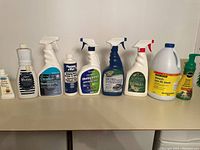Frontal view of various cleaning products lined up on a shelf showing their labels and bottles.