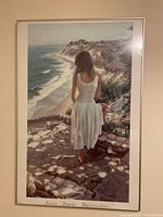 Framed watercolor print titled 'Coastline' by Steve Hanks showing a woman in a white dress on a coastline path, viewed from behind