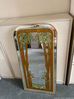 Front view of the mirror showing bamboo design on reflective surface and gold frame.