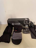 Complete lot showing Savior heated mitts, box, charging cable, and user guide.