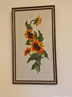 Front view of framed handmade rug hooking of sunflowers with detailed floral design.