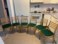 Six wooden ladder-back chairs arranged in a row on tiled kitchen floor