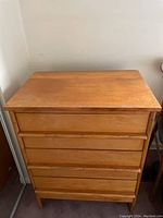 Closed wooden chest of drawers showing overall condition and scuffed top.