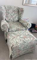 Floral upholstered wingback armchair with matching ottoman, showing front view