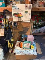 Overview of the baby and kids lot showing stroller, boxed potty step stool, boxed Peg Perego stroller, and assorted baby toys and accessories.