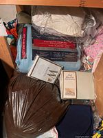 Top view of bed linens and quilts including synthetic down side sleeper pillow, sheet sets, and assorted fabrics packed in plastic bags.