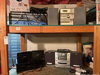 Shelf with various audio components including Sony stereo, Bose speakers, Panasonic DVD recorder with cable box
