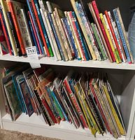 Two shelves filled with assorted children's picture books arranged spine-out on a white bookshelf.