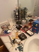 Full tabletop view showing costume jewelry and small toiletry items in various containers and jewelry holders.
