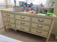 Front view of the nine-drawer Dixie dresser with items on top including a basket, toys, and a small gumball machine.