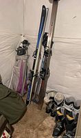 Photo showing Rossignol and other skis with Marker bindings standing upright against a wall next to golf clubs in a bag
