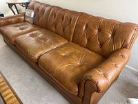 Front perspective of sofa showing tufted cushions and rolled arms