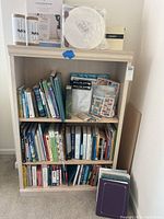Bookshelf with a variety of books including Harry Potter hardcover books along with scrapbooking supplies like plastic sleeves and stickers