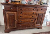 Full front view showing the wooden sideboard's drawers and cabinet doors with a polished brown finish.