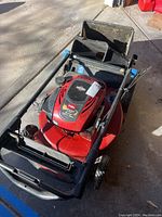 Front angled view of red Toro lawnmower showing engine and handlebars, with attached grass collection bag in rear.