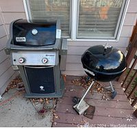 Photo showing a Weber Spirit gas grill next to a Weber round kettle charcoal grill on a patio, with some leaves on the ground