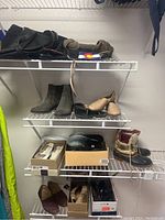 Multiple pairs of women's shoes on wire shelves including boots, moccasins, slippers, and casual shoes.