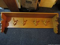 Top view of the pine wooden wall rack showing four peg hooks and goblin-face carved side end panels.