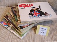 Stack of 8 Giles cartoon books showing the top cover with a British figure holding a torch and shield with the Union Jack.