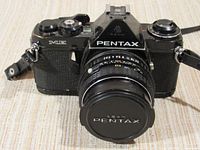 Front view of black Asahi Pentax ME camera with attached Pentax lens and lens cap.