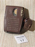 Global 9 transistor radio secured in dark brown leather case with visible ventilation holes and attached earphone pouch on side, front view.
