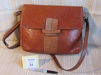 Front view of brown leather shoulder bag with flap and strap.