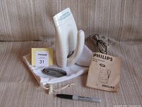 Philips travel steamer with accessories including manual, detachable brush, carry bag, plus a marker pen for scale.