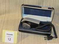 Philishave D9 electric razor placed inside an original felt-lined case with a hinged lid. Case interior is blue felt material with white trim. Razor has three rotary shaving heads and a coiled power cord.