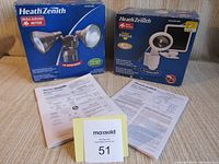 Two original boxed HeathZenith motion-activated outdoor lights with instruction manuals and packing materials.