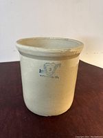 Front side view of the 3 gallon antique stoneware crock placed on a wooden surface with white background.