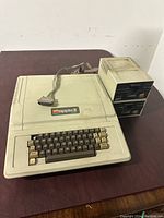 Full view of an Apple II Plus computer with keyboard and two external disk drives.
