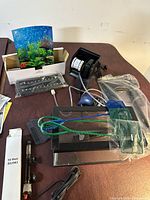 Photo showing assorted aquarium supplies including heater, nets, filter, LED light, lid, tank, power cord, and backgrounds