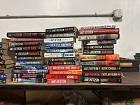 Photo of multiple James Patterson hardcover books stacked horizontally and vertically showing various titles and condition.