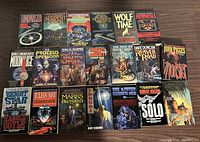 Overview of the 20 vintage sci-fi paperbacks on a wooden surface, showing front covers with thematic artwork and authors' names.