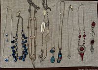 Overview of multiple costume jewelry pieces including necklaces, bracelets, and earrings displayed on fabric.