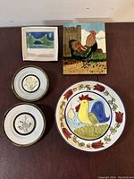Image showing signed ceramic landscape wall art, rooster portrait tile, two Japanese Chokin decorative plates, and large serving bowl with rooster design.