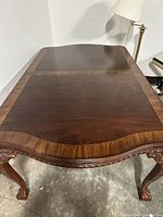 Top of dining table showing two-tone inlaid wood surface and carved edges