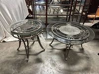Both round glass topped patio tables, coffee table on right, end table on left on concrete floor