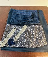 All items stacked showing folded navy blue tablecloth, placemats, napkins, and star pattern runner with tassels.