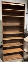 Front view of a tall wooden bookcase with seven shelves showing the natural wood grain finish.