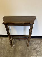 Full frontal view of the vintage wood side table showing the narrowing top and turned legs.