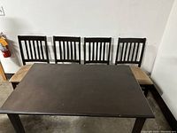 Photo of dark wood rectangular table with four matching chairs without seat pads visible, showing overall set layout.