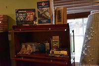 Photo showing a variety of historical collectible items on a wooden shelf including the Wings of Texaco 1932 Northrop Gamma model, bear figurines with coins, books, and smaller items.