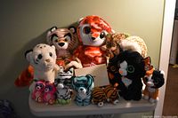 Photo showing large and assorted small Ty Beanie Baby Puffies plush animals, various animal types including tigers, cats, and owls in bright colors, some with tags.