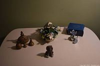 Wide view of all items on table including flower basket, music box, pewter lion, and brass bells