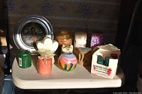 View of various candles including votives, heart-shaped, and novelty shaped candles plus a decorative Columbus Quincentennial commemorative plate.