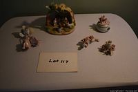 Photo showing all porcelain items in the lot including the nativity scene, rose candleholder, and rose figurines.
