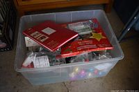 Top view of plastic storage bin showing red Holly Jolly sampler kit and other assorted Christmas ornaments inside
