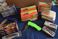 Overview of various boxed folding knives, cutters, and Victorinox tins showing lot contents